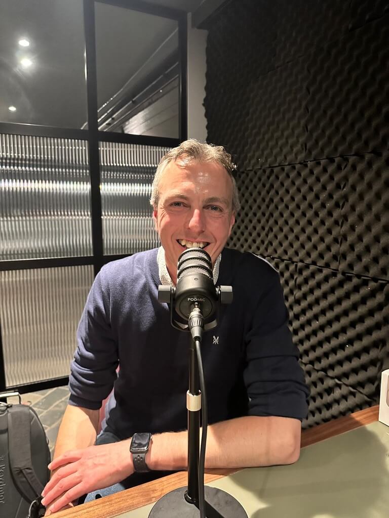 Justin Neale in front of a microphone recording a podcast about value pricing and customer experience