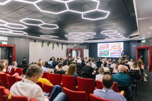 View from the back of a large audience with Justin Neale presenting on stage showcasing how Nurofen offered essentially the same product but at very different price points